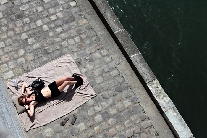Parisian girl sunbathes on the Seine river bank