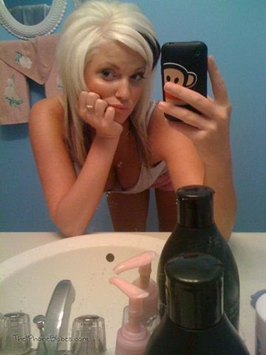 young teen girl taking pictures in a mirror with iphone