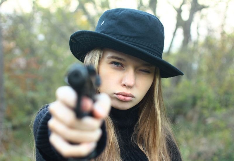 cute young blonde girl shows her long hair with gun