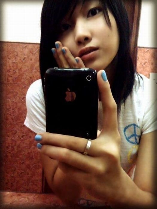 young teen girl taking pictures in a mirror with iphone