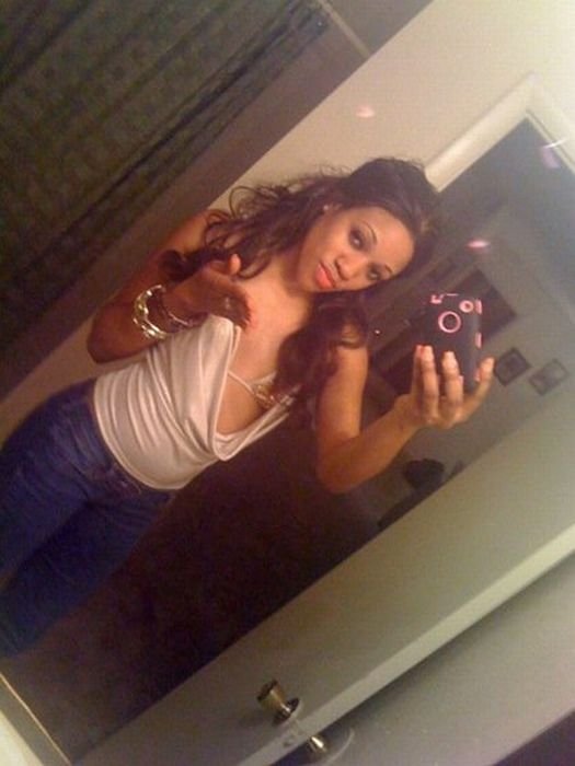 young teen girl taking pictures in a mirror with iphone