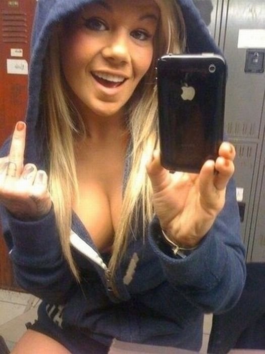 young teen girl taking pictures in a mirror with iphone