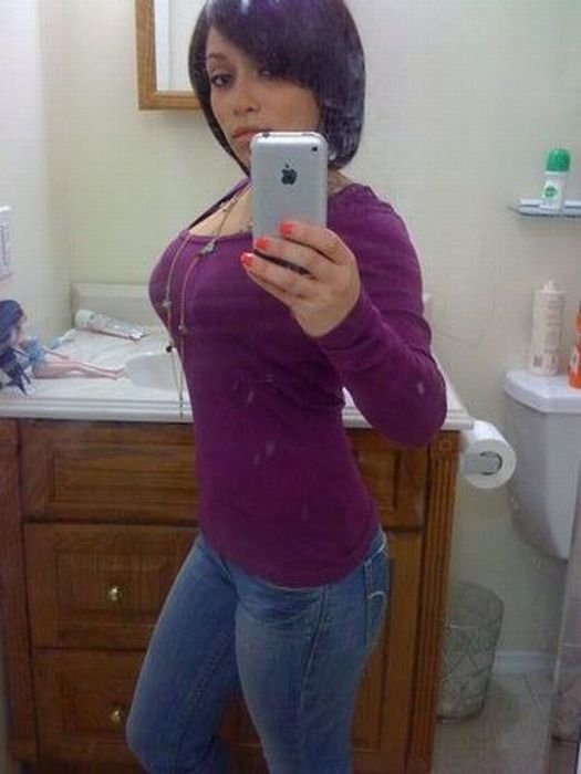 young teen girl taking pictures in a mirror with iphone